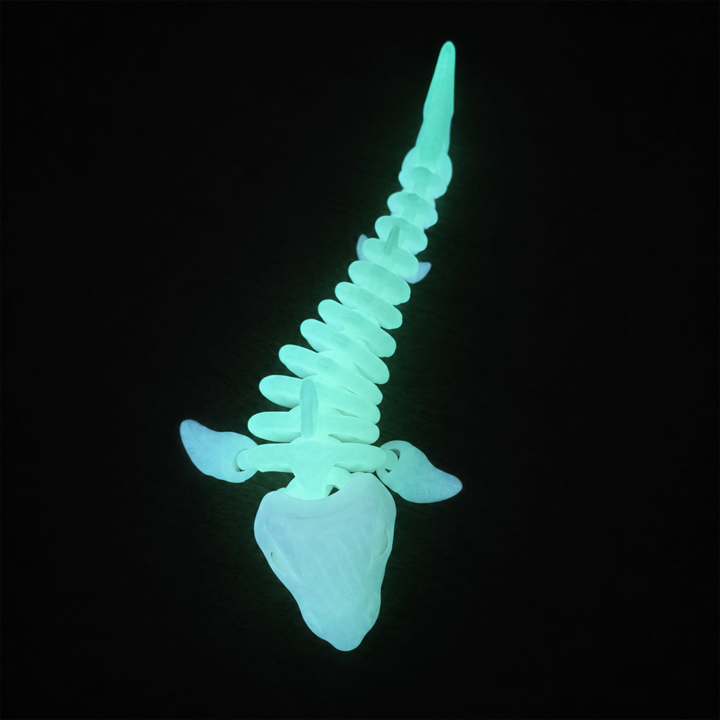 A glowing, bioluminescent-looking fish skeleton model or toy shown against a solid black background.