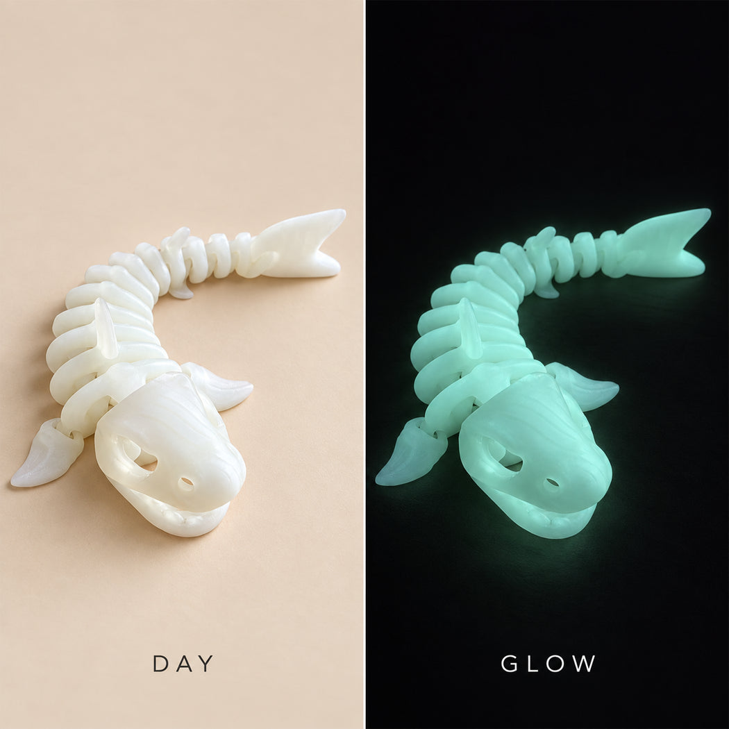 A split comparison of a 3D-printed fish skeleton toy, showing its appearance under normal light on the left ('DAY') and its glowing pale green color under the dark on the right ('GLOW').