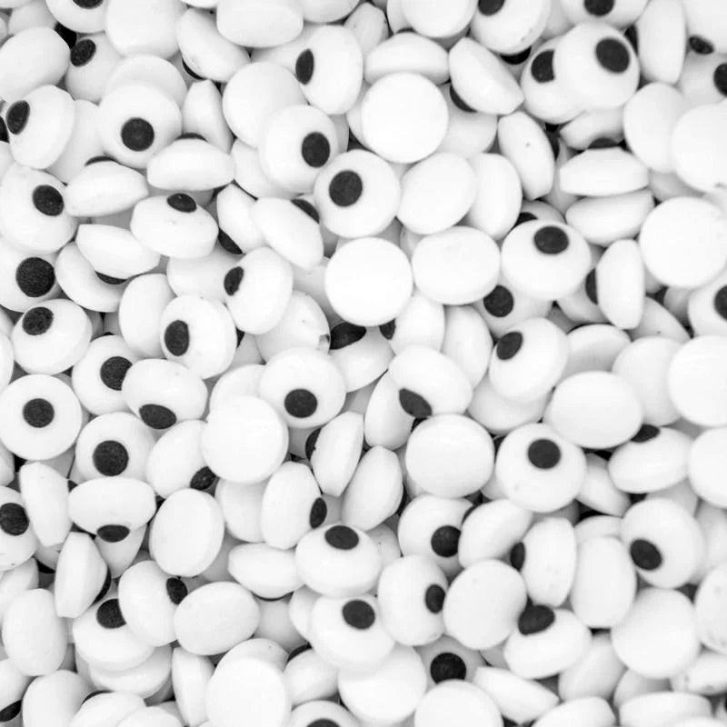 Close-up of a large collection of white candy eyes with black centers.