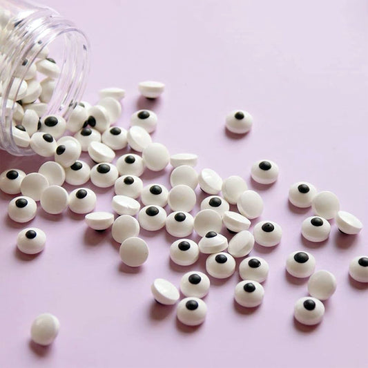White googly eyes with black centers scattered on a pink background
