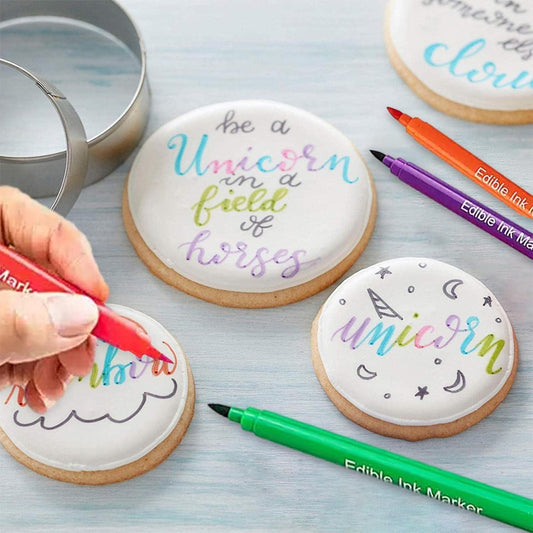 Decorative cookies with colorful text and markers on a light blue surface