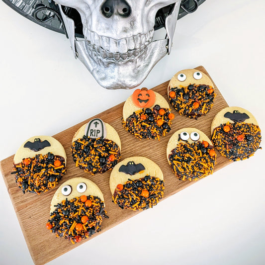 Halloween-themed cookies on a wooden board with a skull in the background