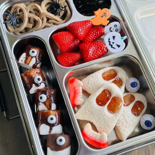 Halloween-themed snack tray with cookies, strawberries, and other treats.