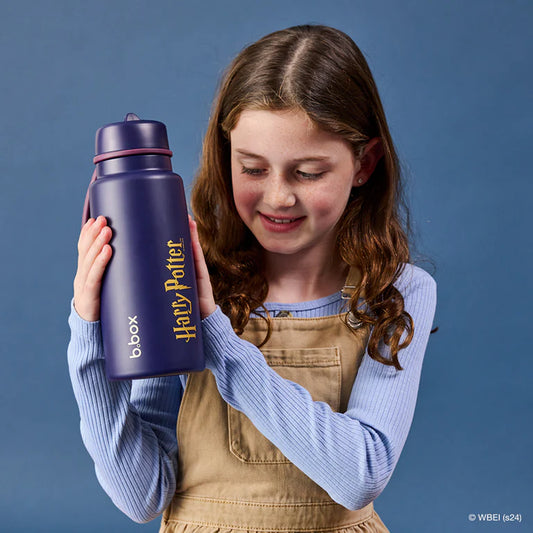 Young girl holding a purple water bottle with 'b.box' branding against a blue background