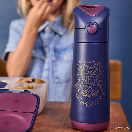 Purple thermos with Harry Potter design on a table with a blurred person in the background.
