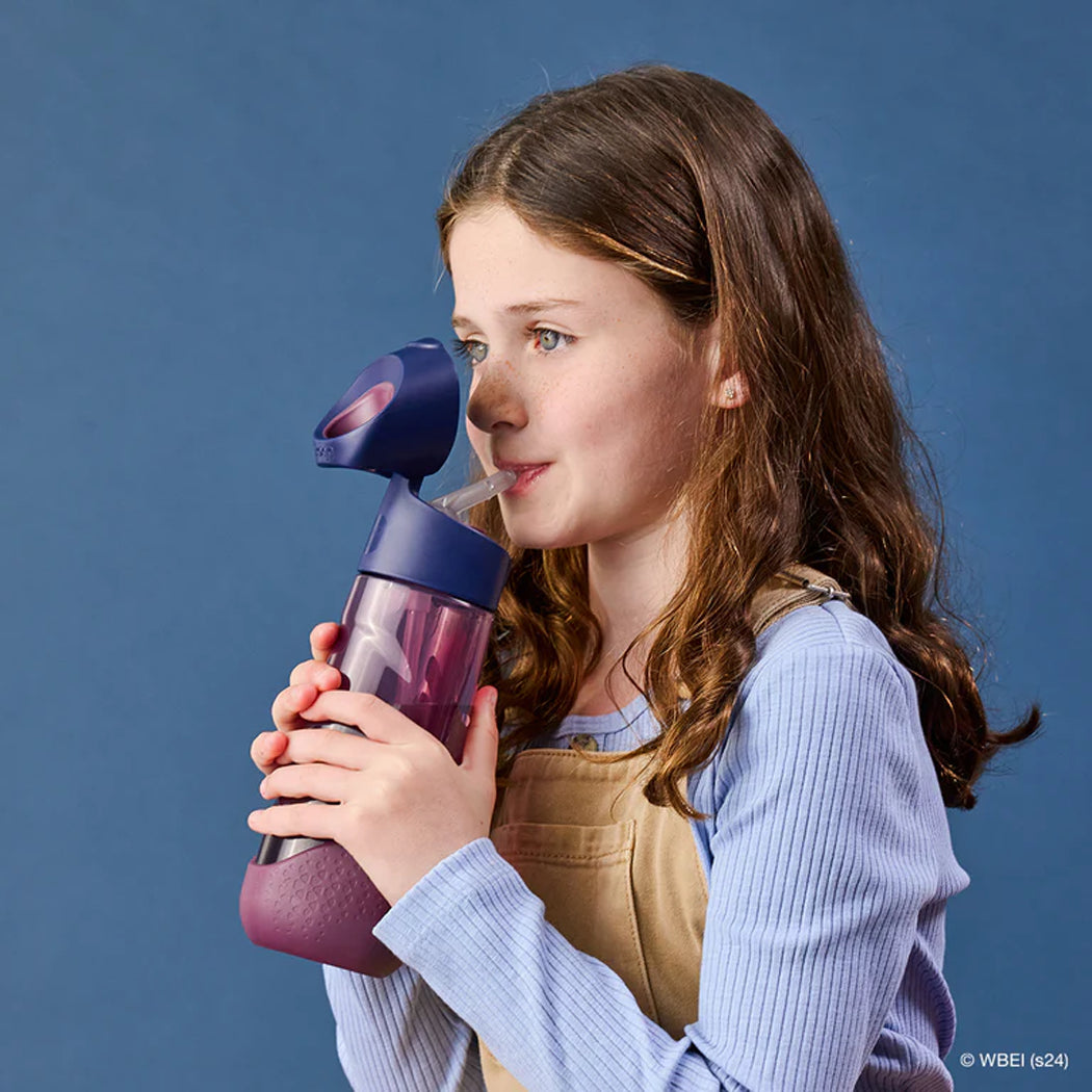 Young girl holding a purple and blue water bottle against a blue background