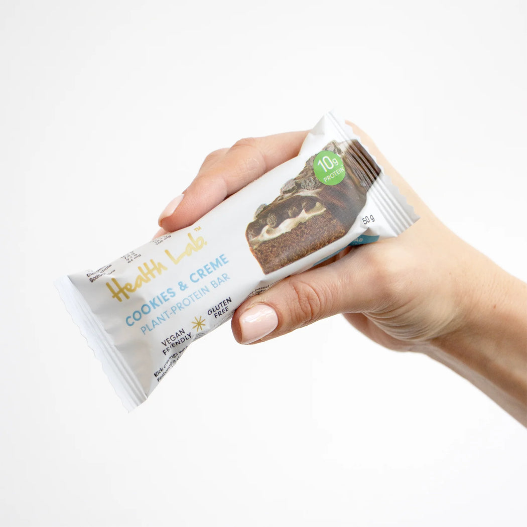 Hand holding a plant-based protein bar with visible branding on a white background