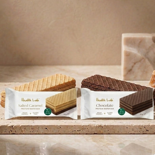 Two Health Lab protein waffer bars, one salted caramel and one chocolate, on a wooden surface.