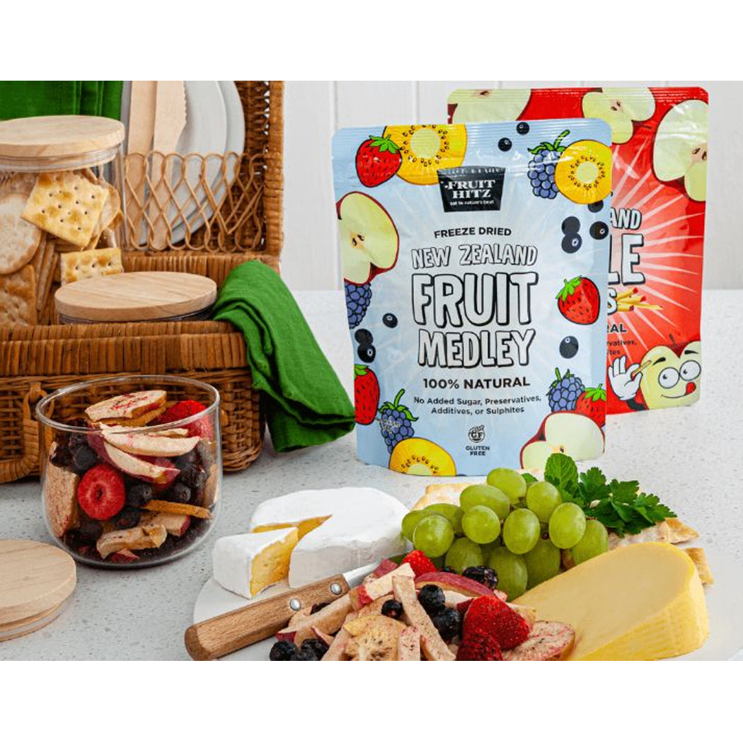 Fruit medley packaging with a cheese platter and fruit on a table