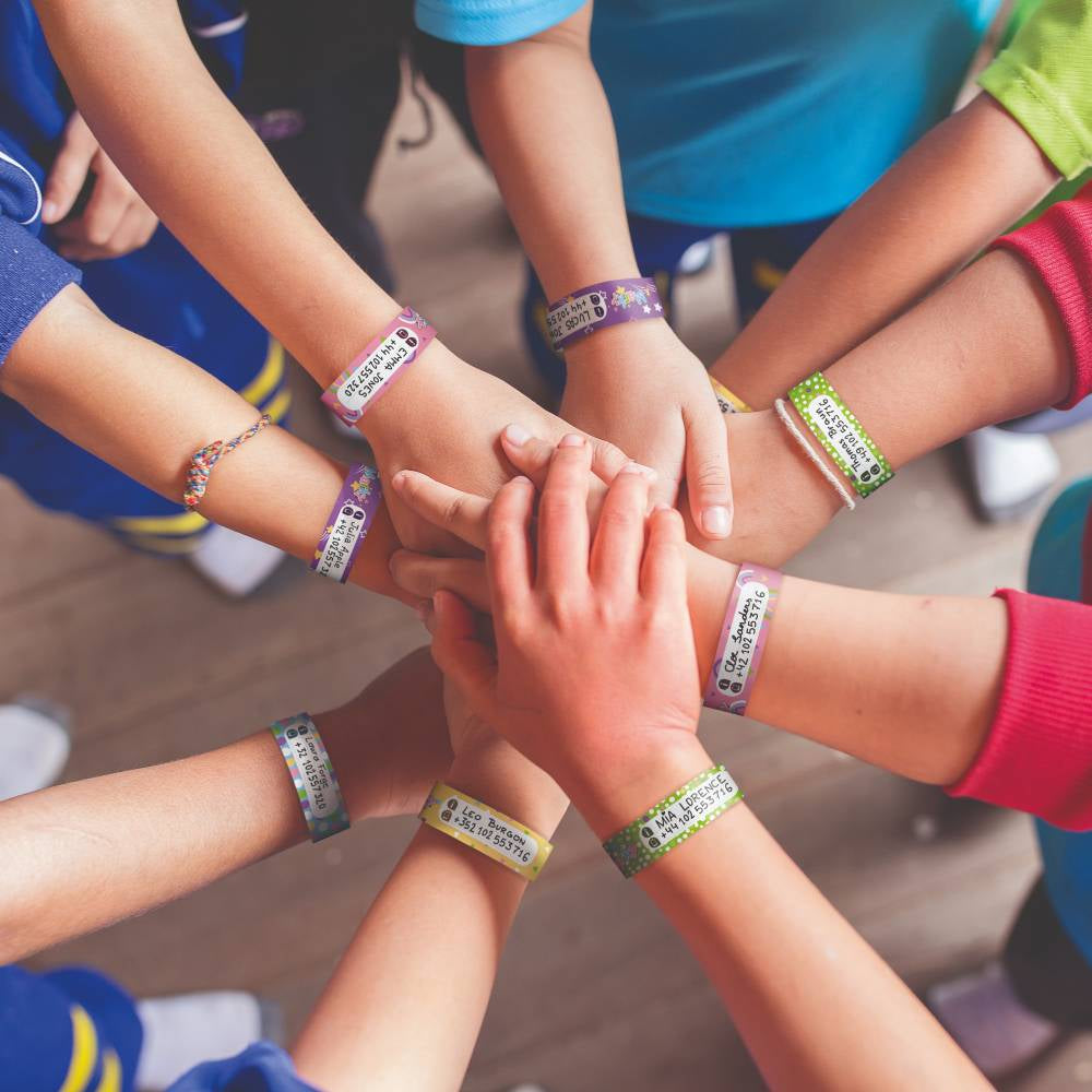 Children's hands with colorful wristbands stacked together in a circle.