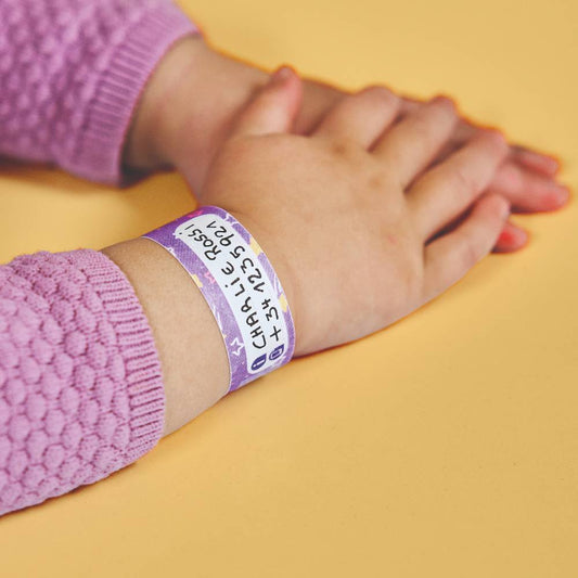 Child's arm with a purple wristband on a yellow background