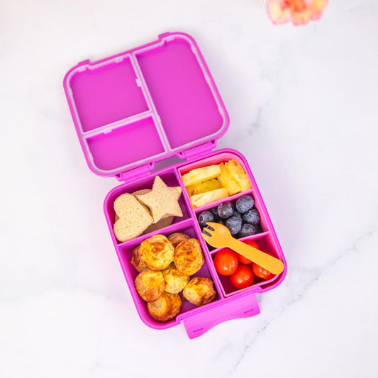Pink bento box with compartments filled with snacks on a white background