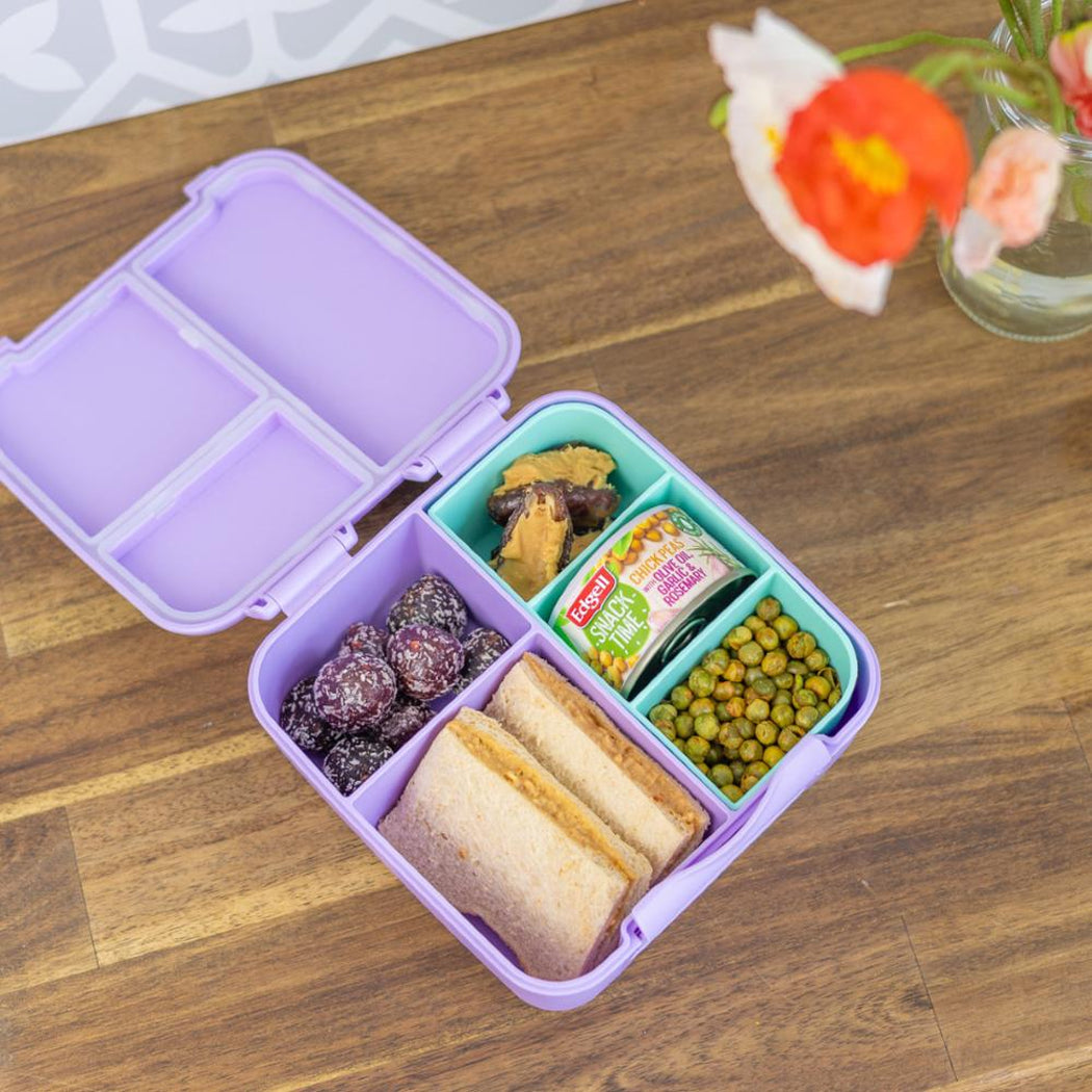 Purple bento box with compartments filled with snacks on a wooden table.