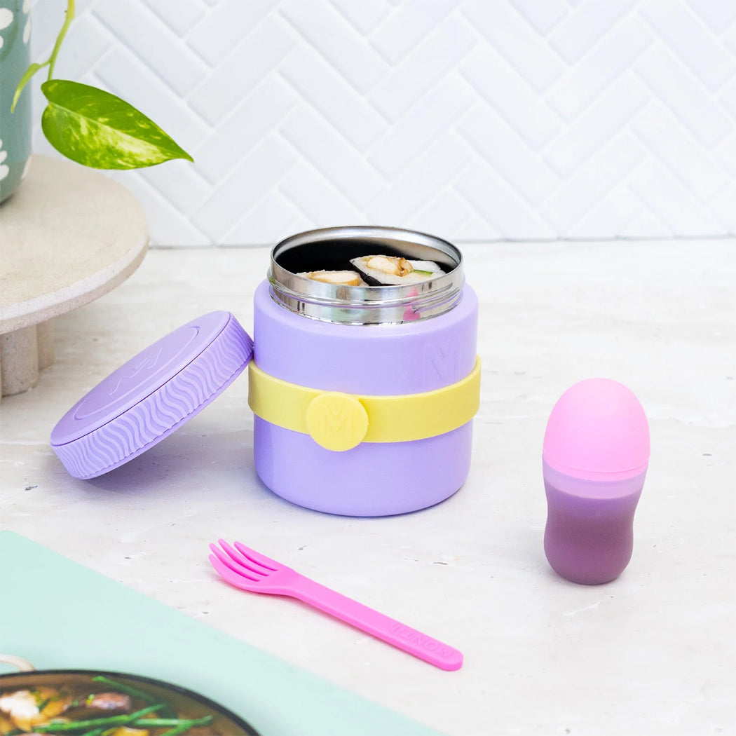 Purple food jar with yellow band, pink fork, and small pink container on a light wooden surface.