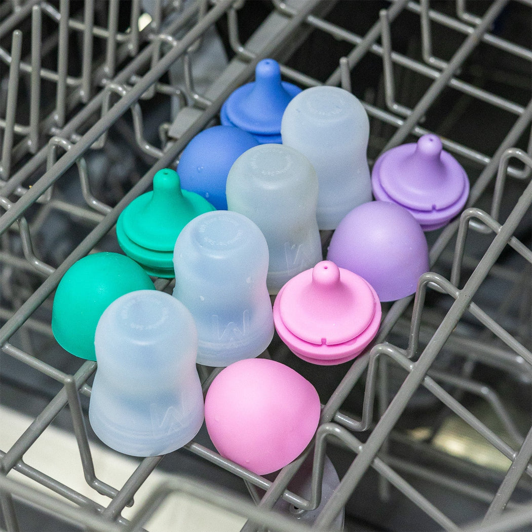 Colorful baby bottle caps on a dishwasher rack