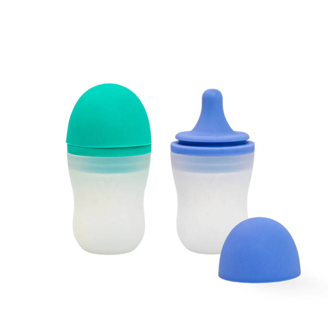 Two baby bottles with blue and green lids on a white background