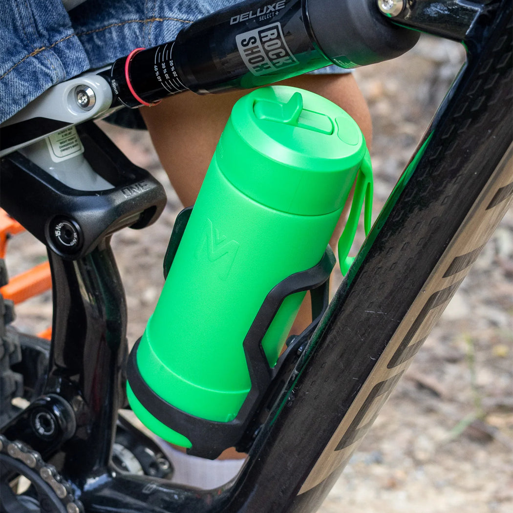 Green water bottle attached to a bicycle frame with a blurred background