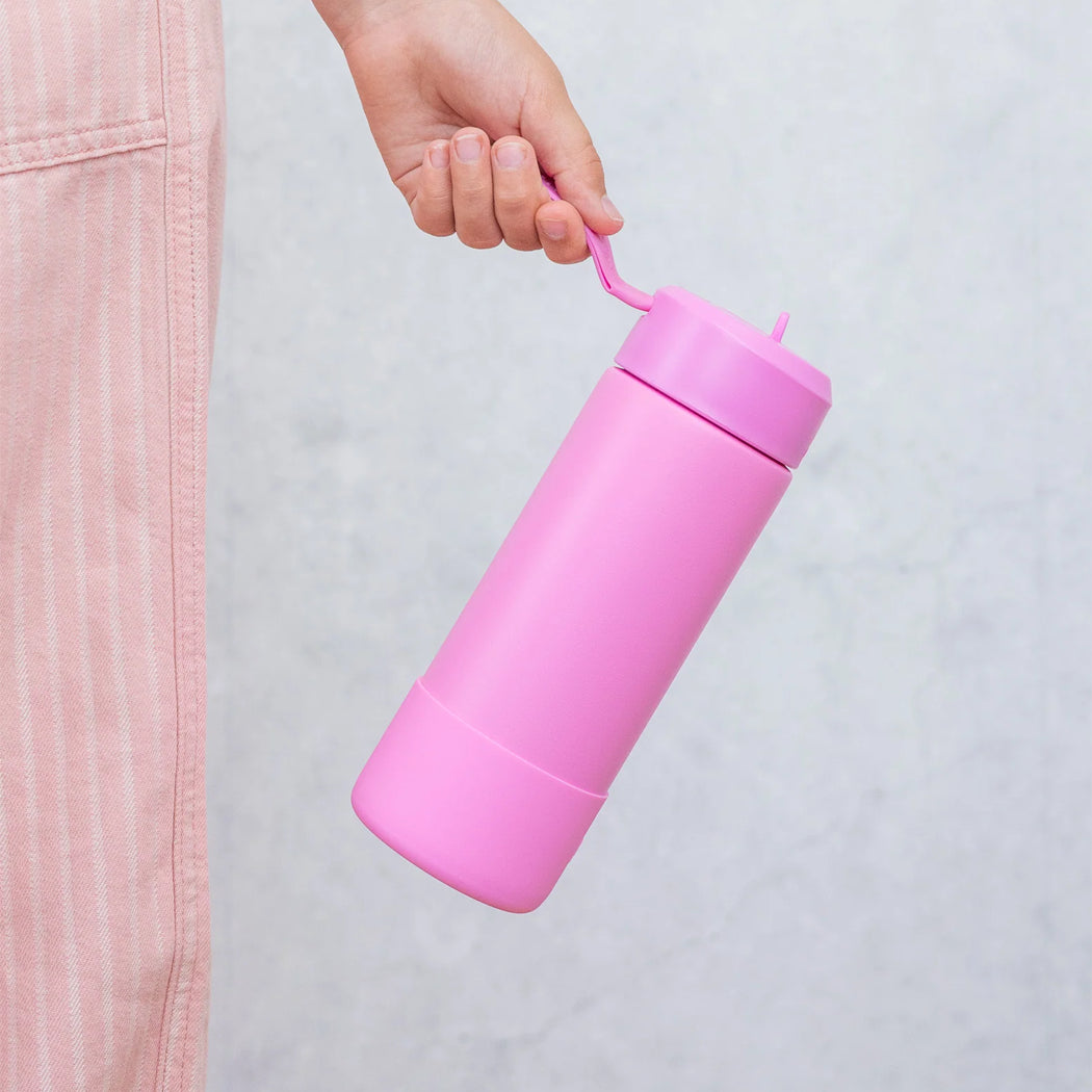 Hand holding a pink water bottle against a light gray background