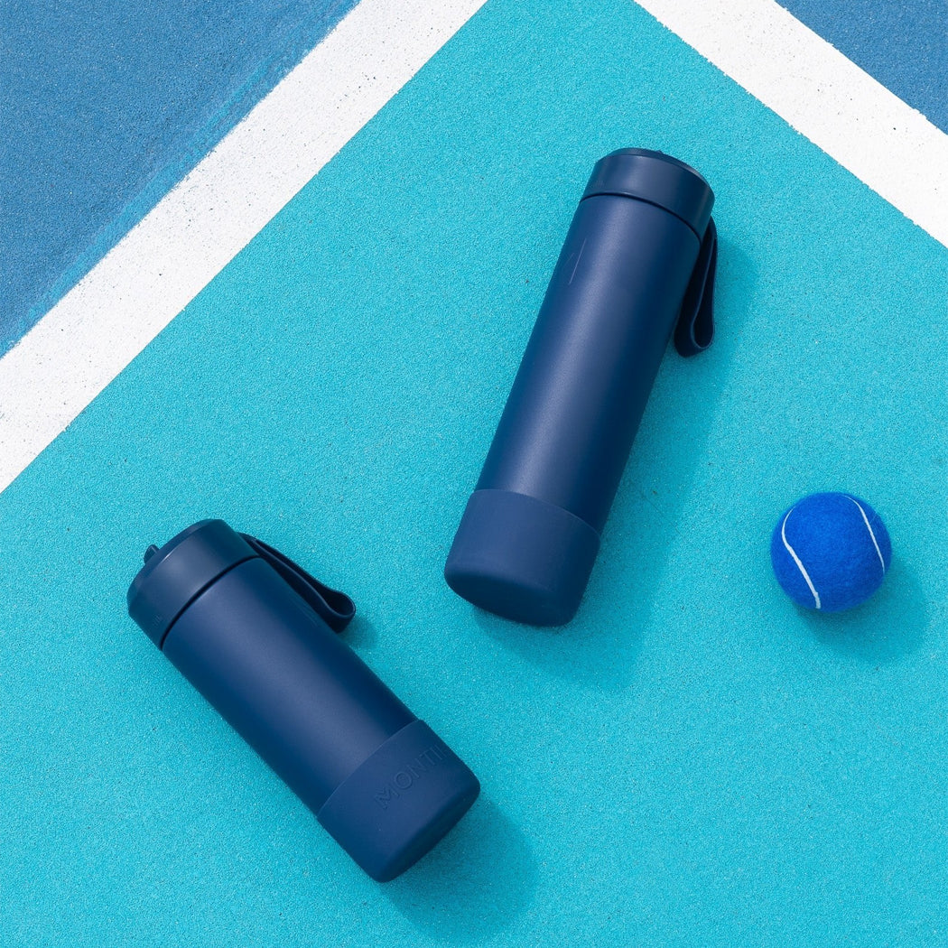 Two blue water bottles and a blue tennis ball on a blue and white surface