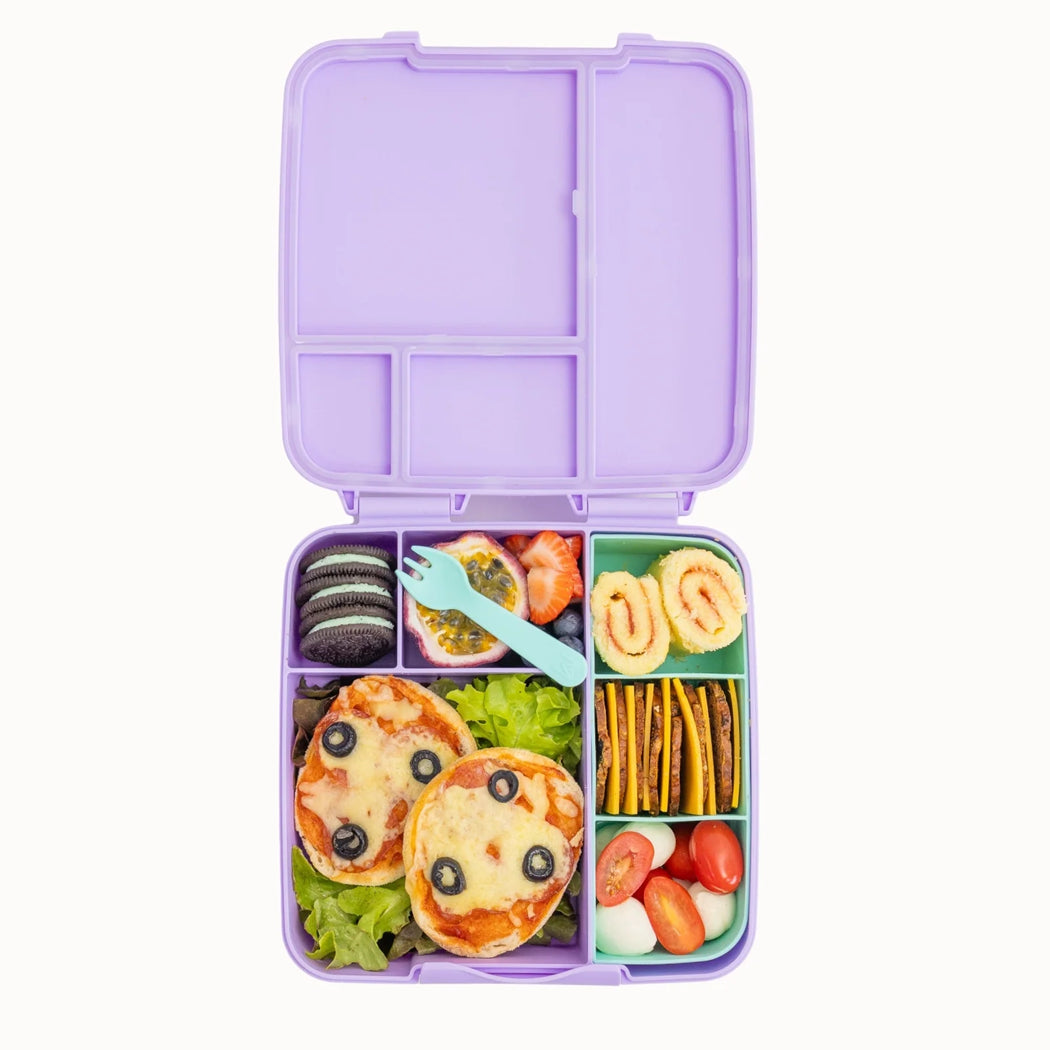 A lavender purple bento lunch box with multiple compartments, shown open and filled with a colorful, playful children's meal including mini pizzas, fruit, crackers, and a small light blue spoon on a white background.