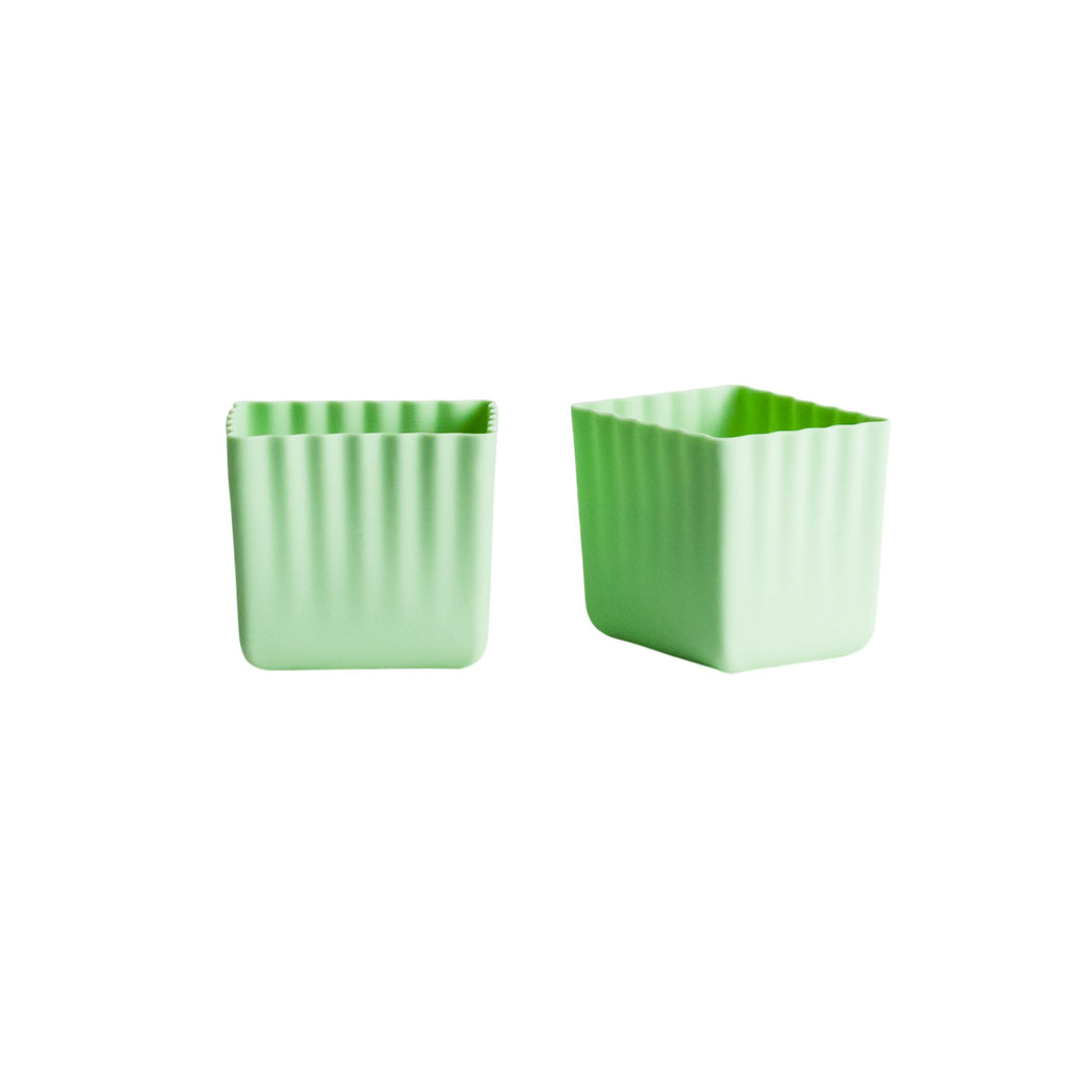 Two light green square silicone containers with vertical fluted sides, shown on a plain white background.