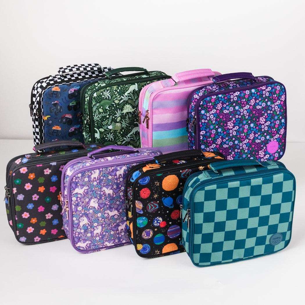 A group of eight patterned lunch bags arranged together on a light gray studio background. The bags feature various designs including floral prints, animal motifs, planets, checkers, stripes, and solid colors.