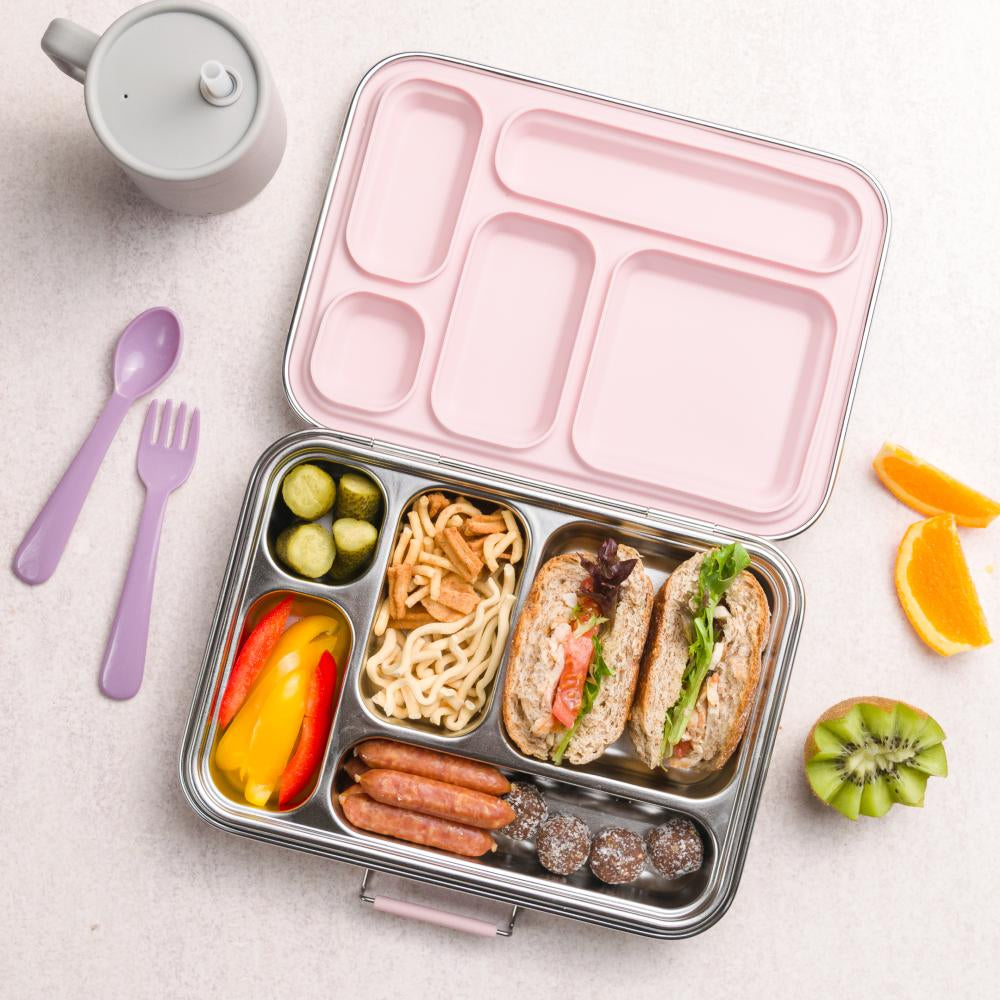 Bento box with compartments filled with food, including sandwiches and vegetables, on a light surface.