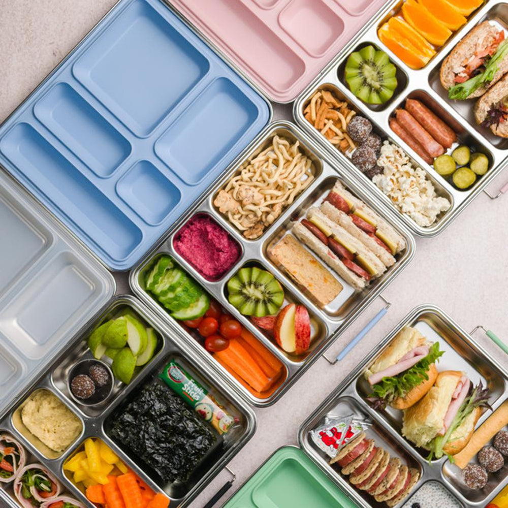 Assorted lunchbox contents including sandwiches, fruits, and vegetables on a light surface.