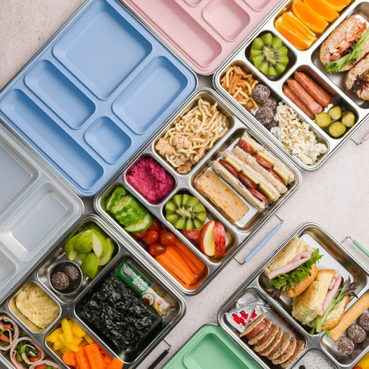 Assorted lunchbox contents including sandwiches, fruits, and vegetables on a light surface.