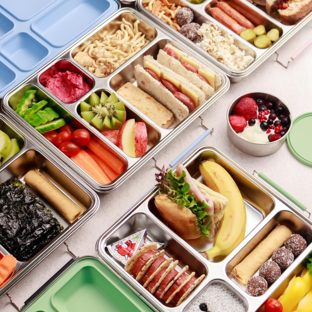Assorted lunchbox contents including sandwiches, fruits, and vegetables on a white surface.