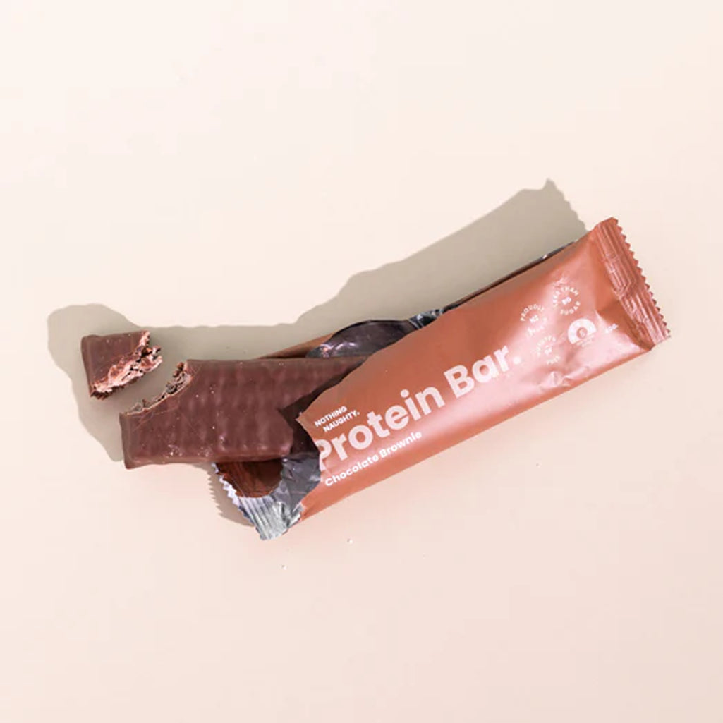 Protein bar with a bite taken out of it on a light pink background