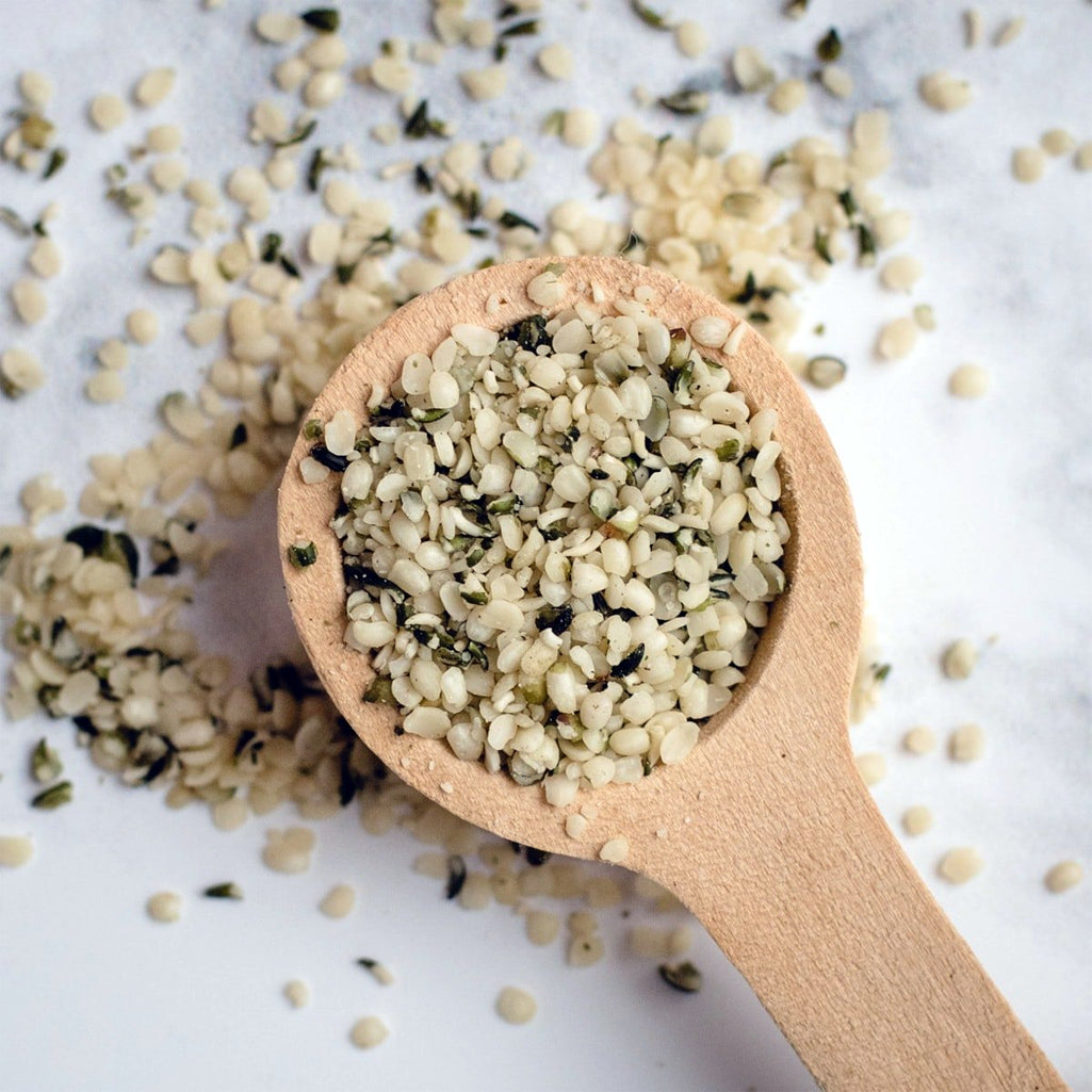 Wooden spoon filled with hemp seeds on a light background