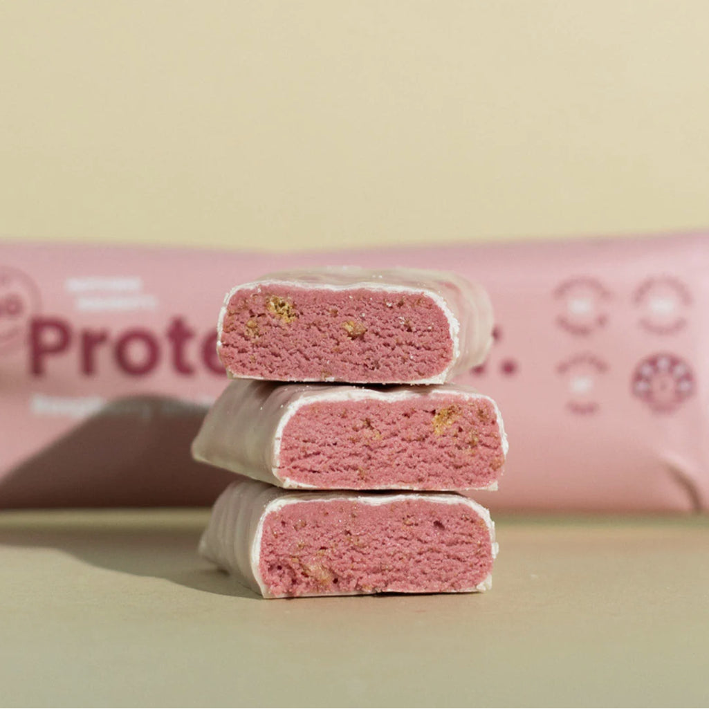 Stack of pink protein bars with a pink packaging roll in the background