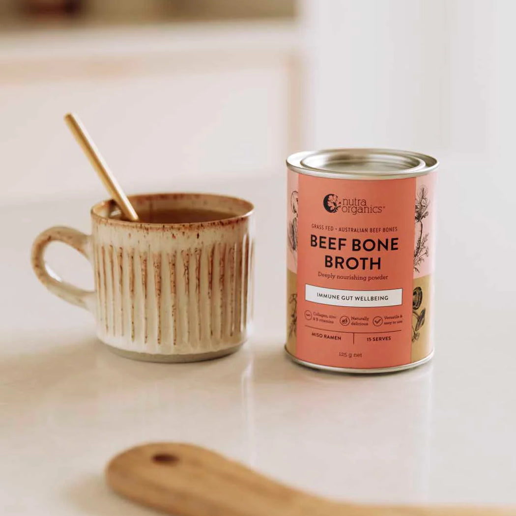 Can of beef bone broth next to a mug on a kitchen counter