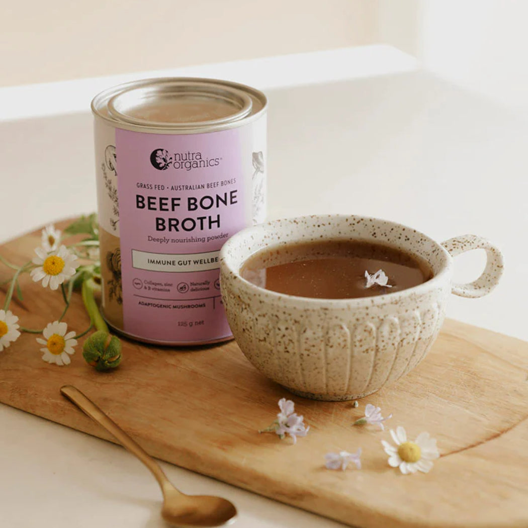 Beef bone broth can and cup on a wooden board with flowers