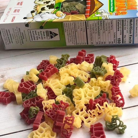 Colorful pasta shapes on a white surface with a box in the background