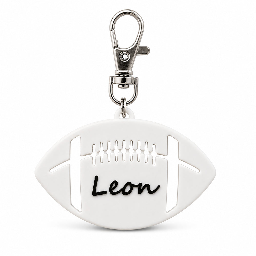 A white football-shaped keychain tag with the name 'Leon' personalized in black script, attached to a silver metal clasp on a white background.