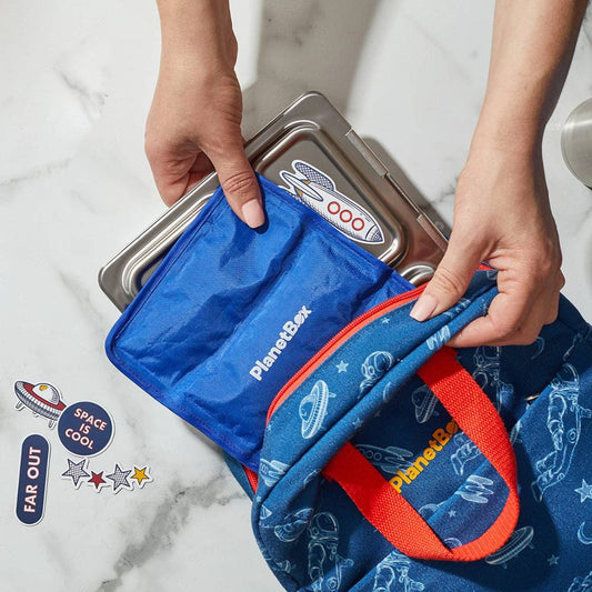 Person opening a blue PlanetBox lunch bag on a marble surface
