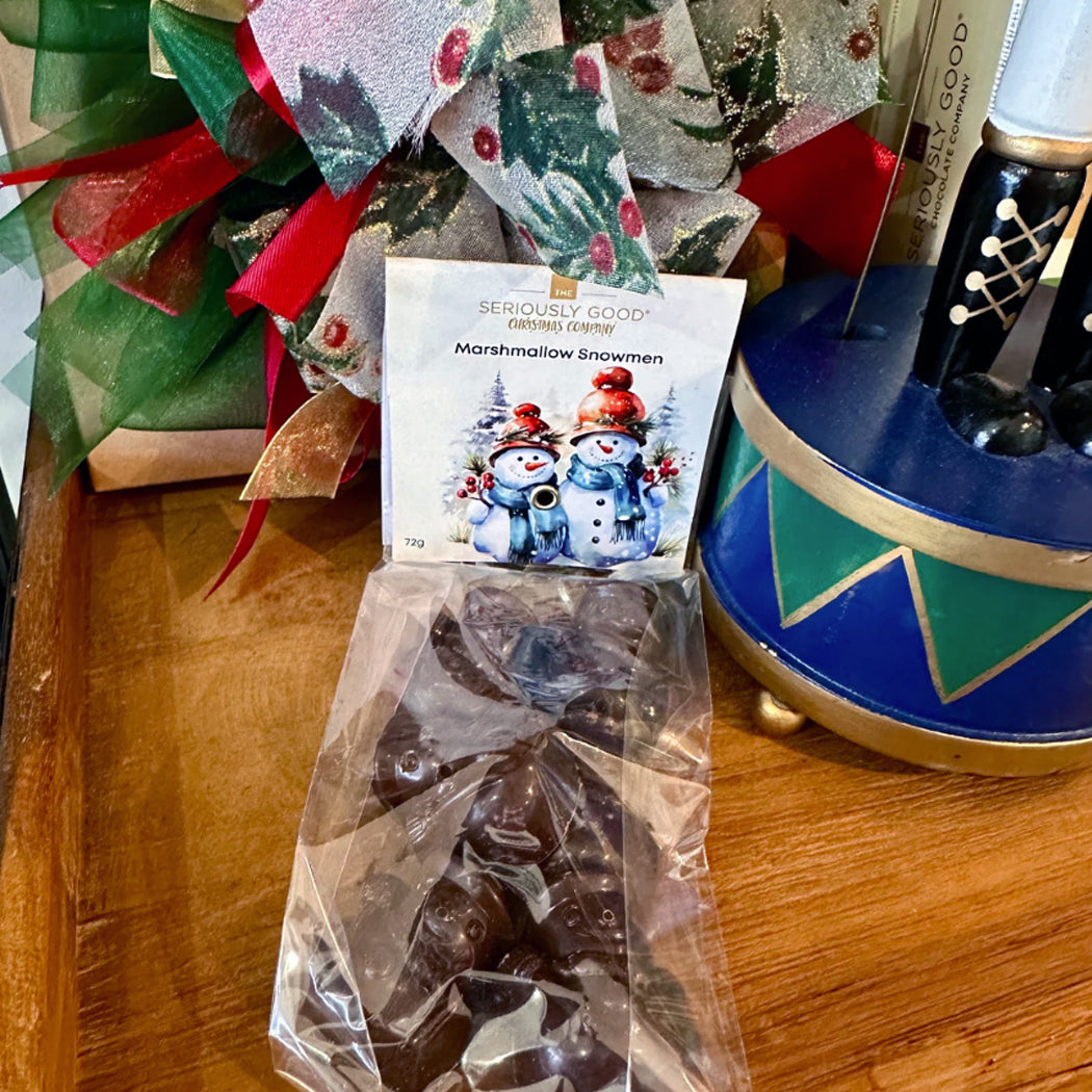 Packaged chocolate, marshmallow snowmen, and a blue and gold decorative item on a wooden surface.