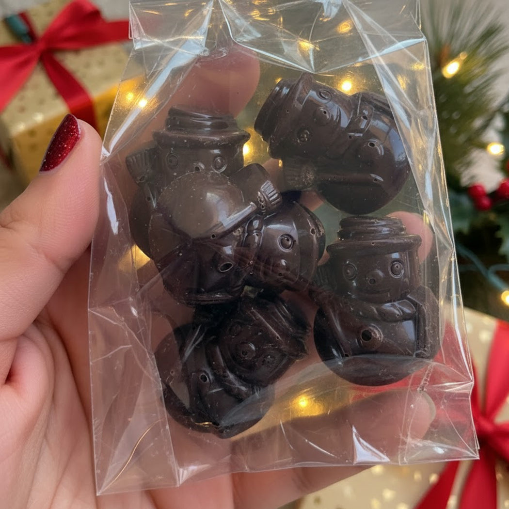 Chocolate robot candies in a clear bag held by a person with a festive background.