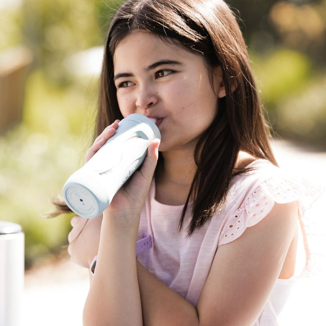 Woman drinking from a white tumbler outdoors