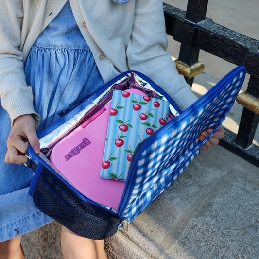 Person holding a blue mesh bag with pink and cherry-themed items.