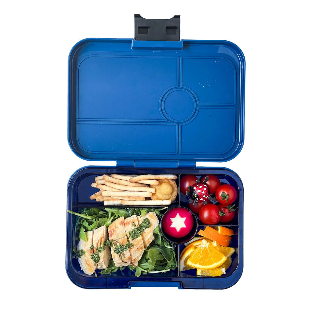 Blue bento box with compartments filled with food on a white background
