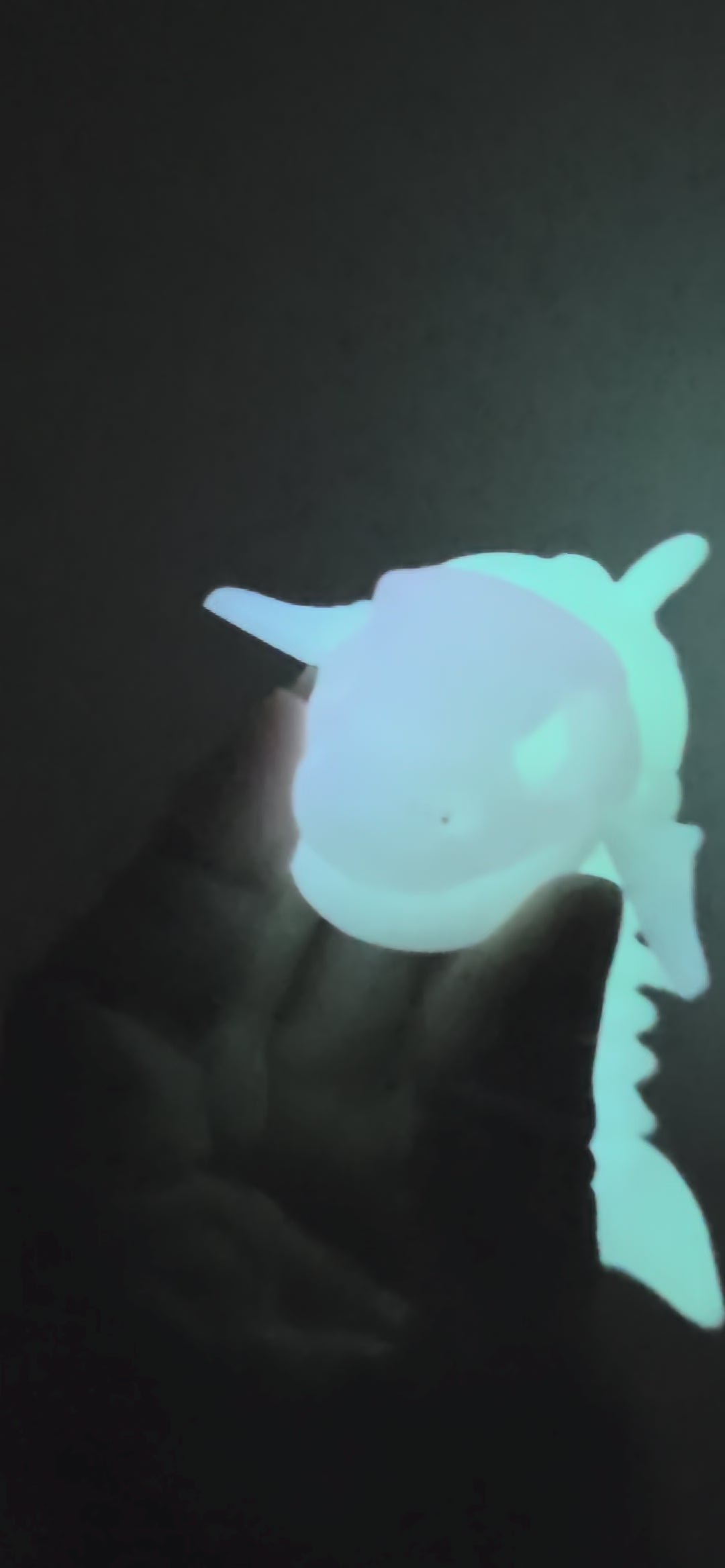 A glowing, bioluminescent-looking fish skeleton model or toy shown against a solid black background.